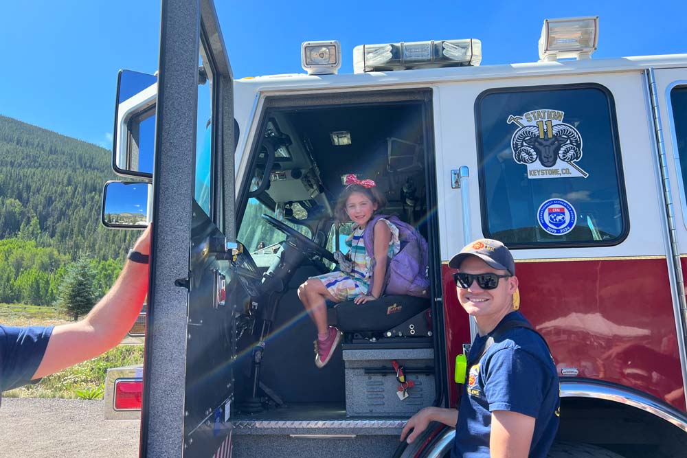 Day camper meeting local fireman and sitting in the firetruck