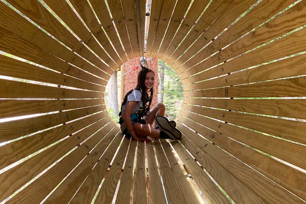 Day camper moving through a tunnel at the Ropes Course at Arapahoe Basin.
