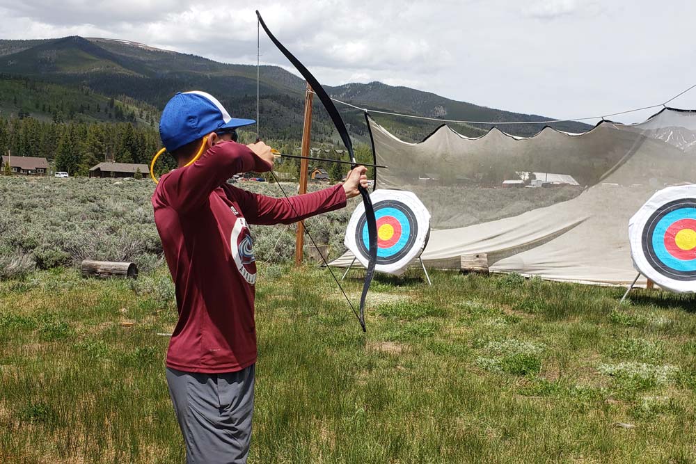 Pathfinders camper learning archery in the sage field