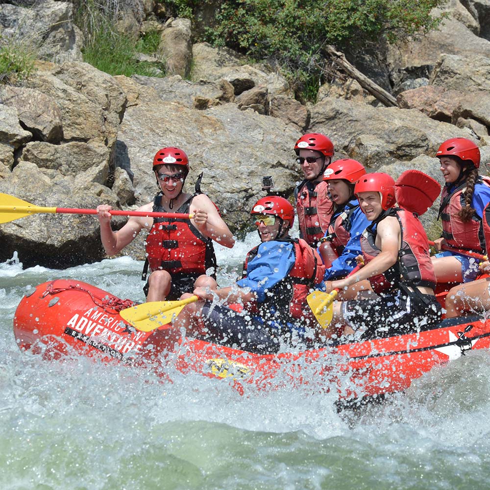 A group headed down the rapids in an inflatable raft.