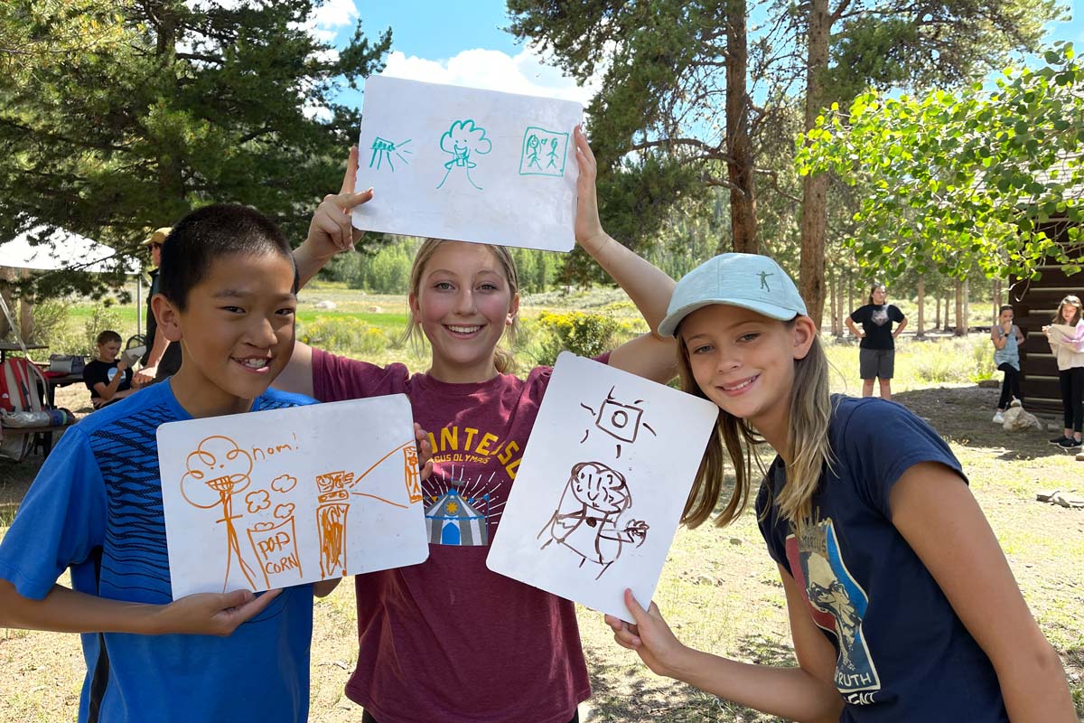 Three Outdoor Education students showing their forest ecology sketches.