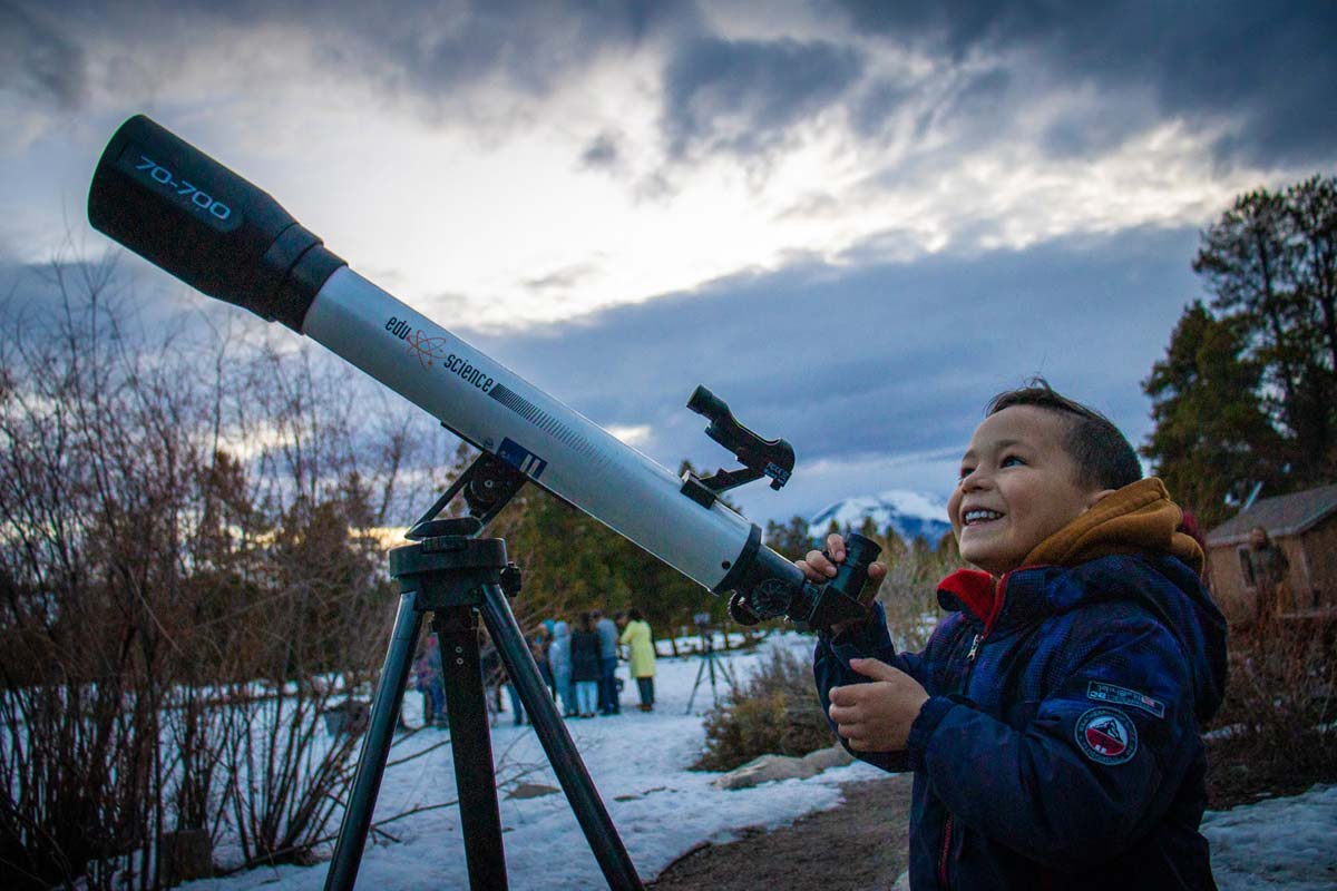 A local Summit County student smiles after looking through a telescope at the stars in our Silverthorne Overnight Outdoor Education program.