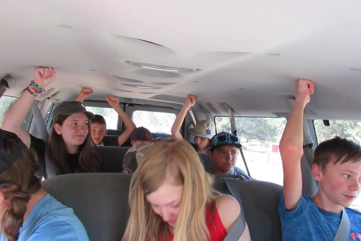 Campers doing "knuckles for buckles" letting the counselor know they have seatbelts buckled