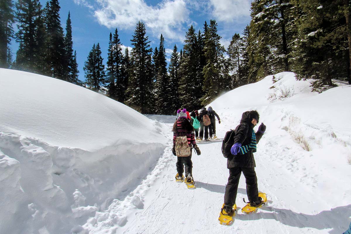 Students work their way down the trail on snowshoes during a field day.