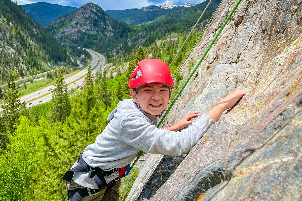 A camper smiling at the camera while rock climbing in the Ten Mile Canyon.