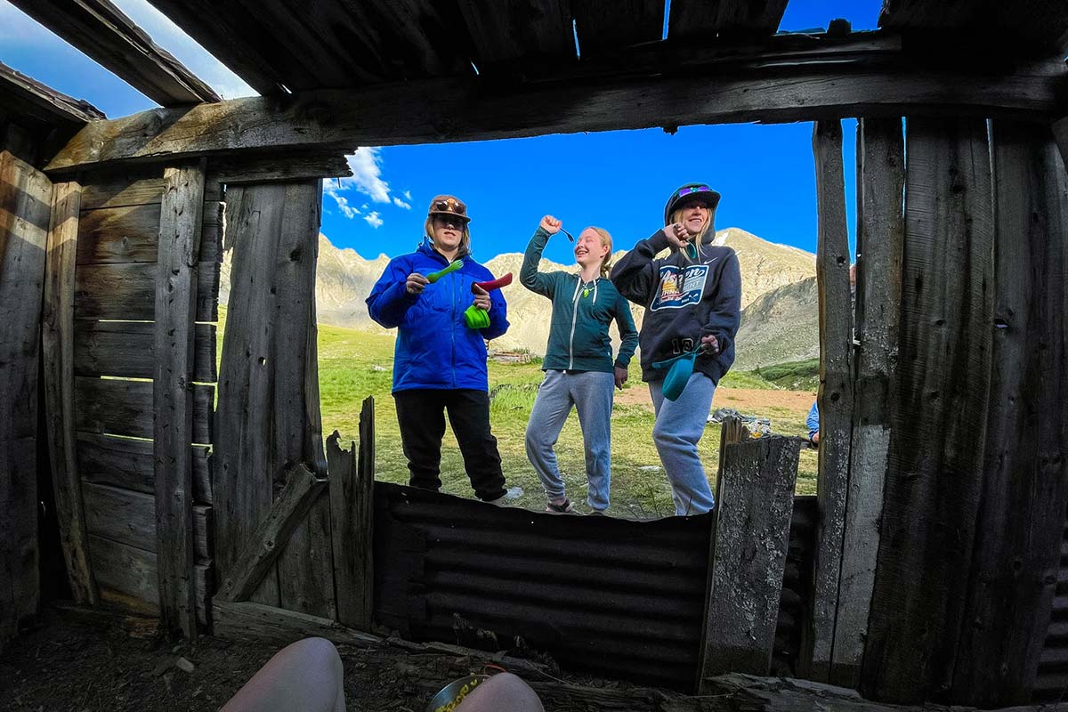 Three CAPs pose outside of an old mountain cabin