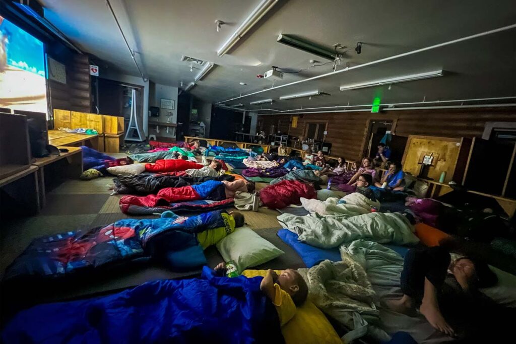 Campers and counselors watching a movie during the Day Camp Overnight
