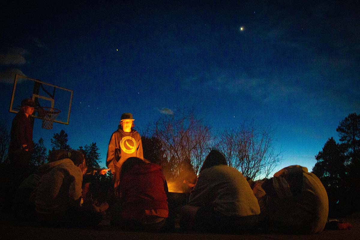 Students sit and look at the stars during a campfire in Girls in STEM Biomedical