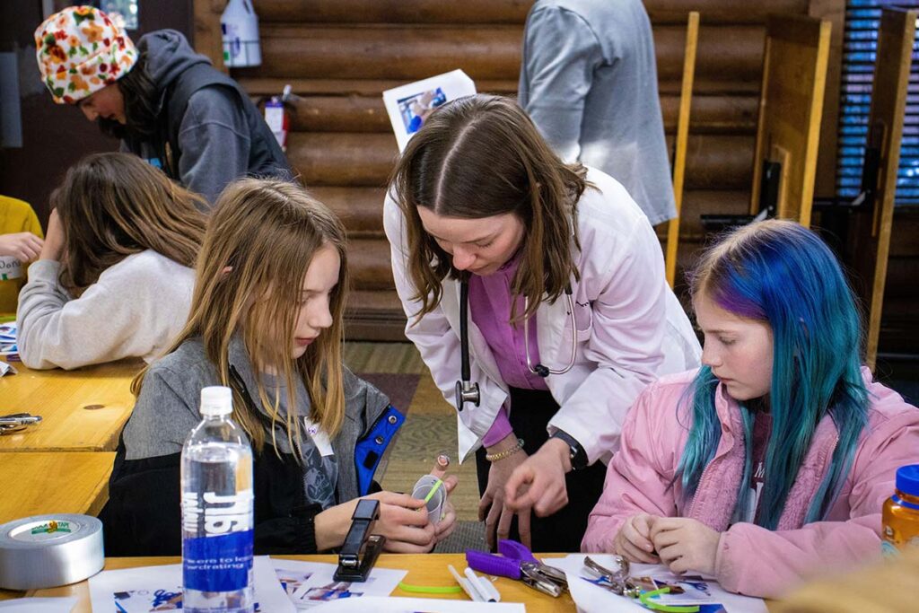 Female mentor working with students in Girls in STEM Biomedical weekend on campus
