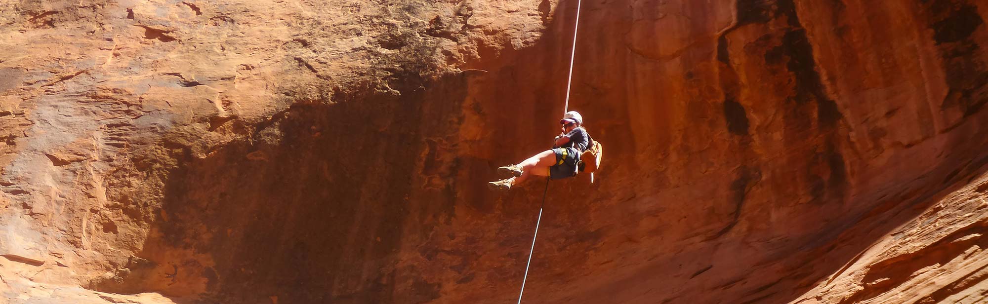 Rappelling down the canyon wall in the desert rocks.