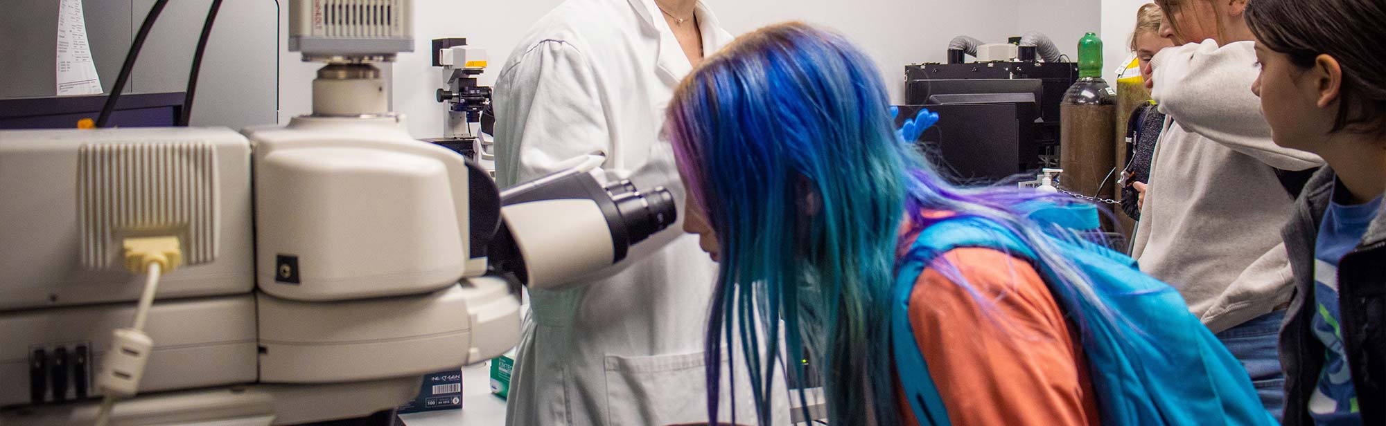 Student looks through a microscope in Girls in STEM Biomedical program