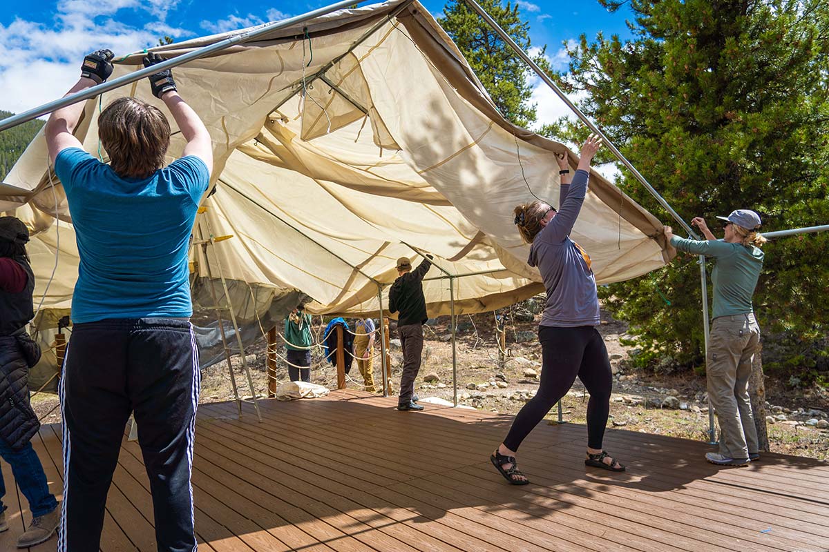 Volunteers and staff raise a tent in Snake River Village on Spring Volunteer Day