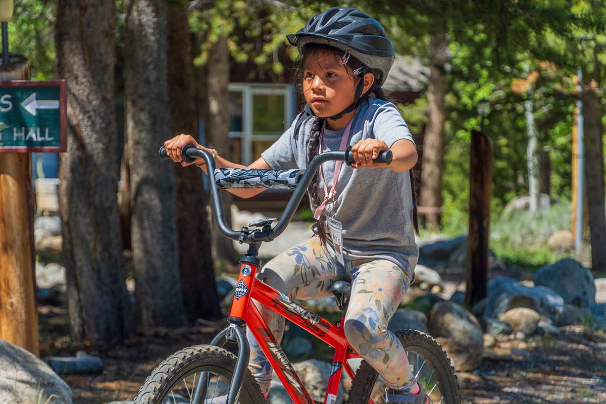A Day Camp girl riding a bike through the campus path