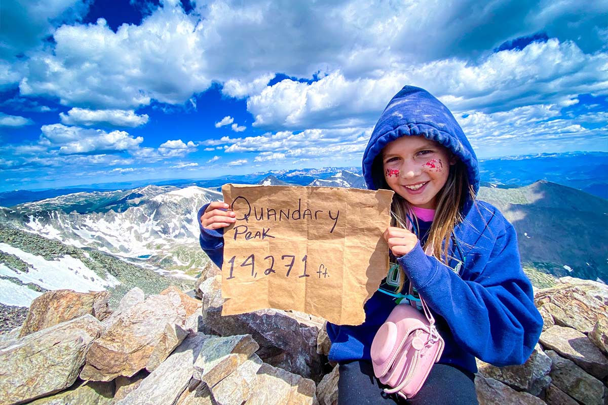 A girl poses atop Quandary Peak above 14,000 feet
