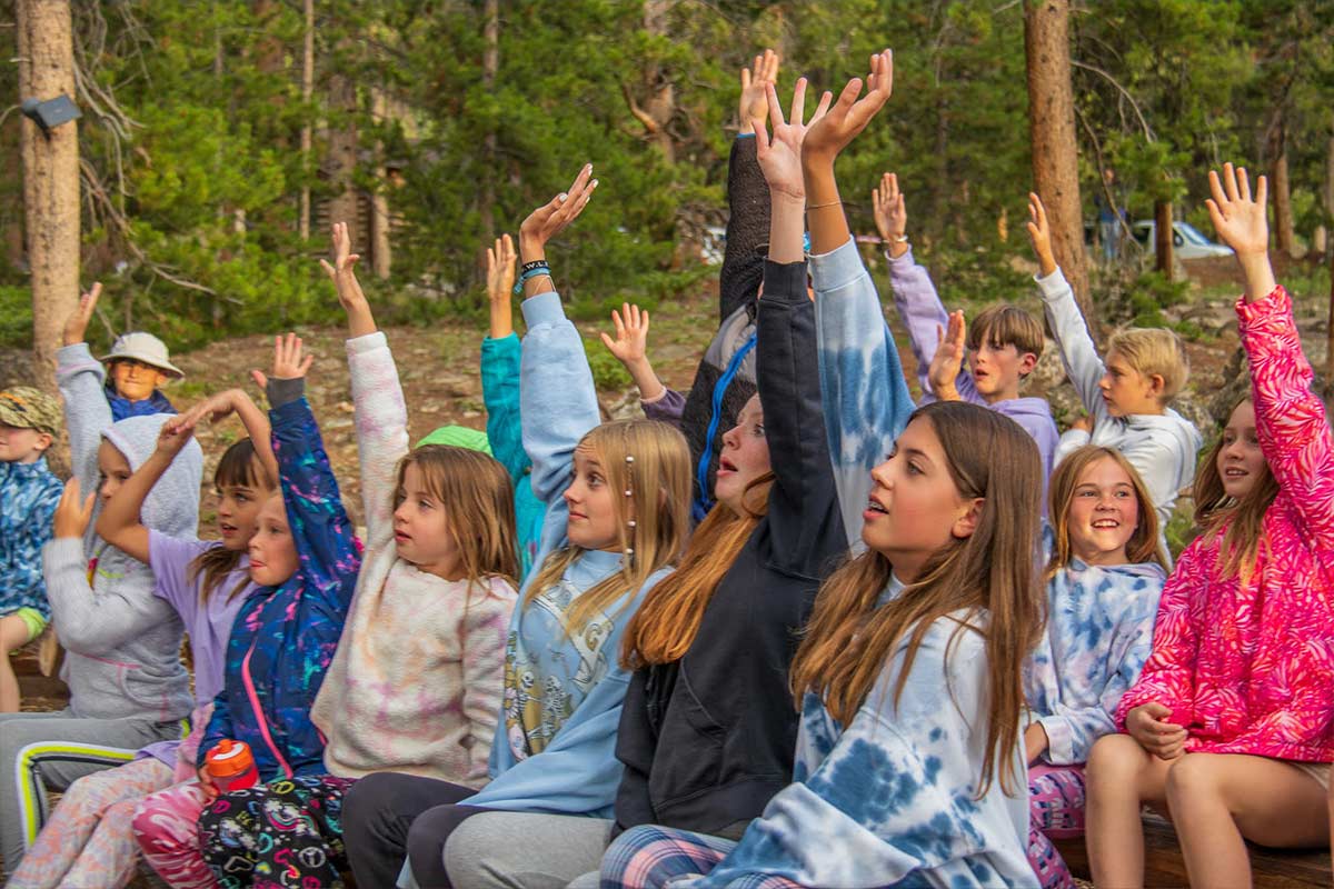 Campers raising their hands during the weekly Campfire.